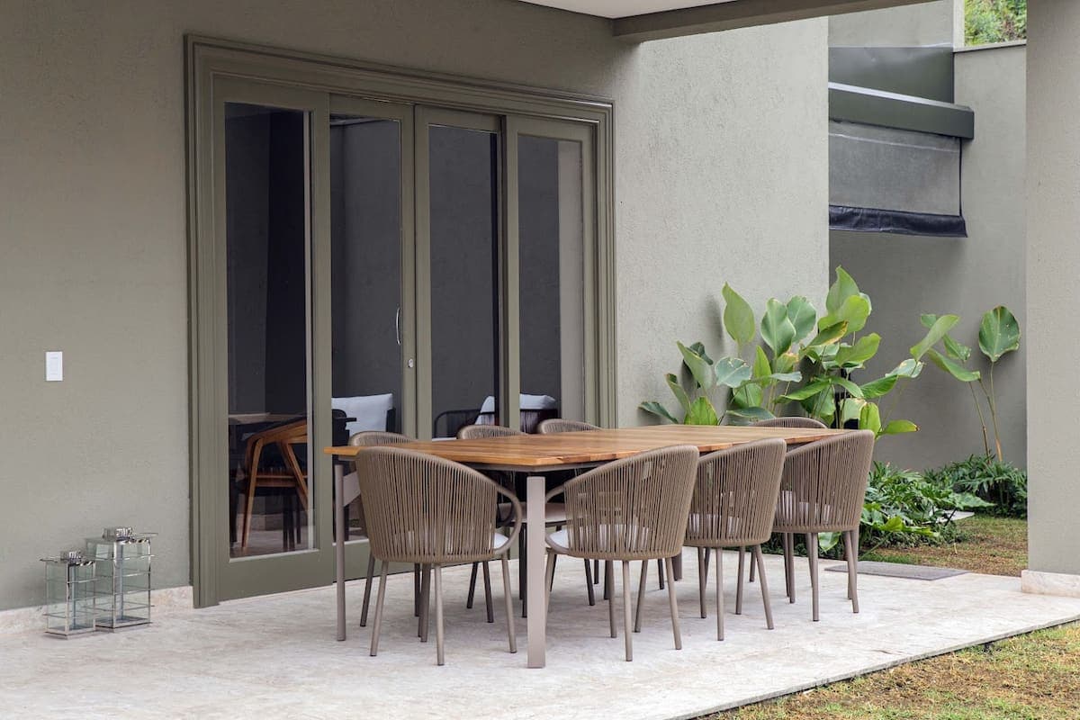 Varanda com mesa e cadeiras voltada para o jardim